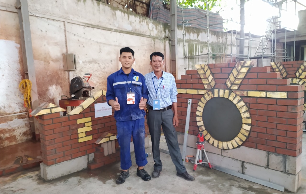 Sinh viên Moong Văn Kỳ  bên cạnh bài thi xây gạch của mình